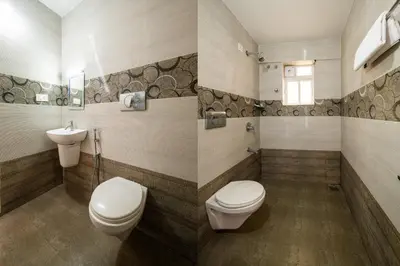 a bathroom with two toilets and a sink at Daan Temple Inn in Guruvāyūr