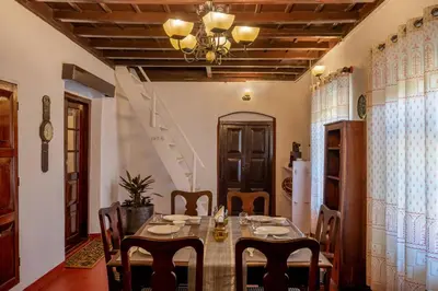 a dining room with a table and chairs and a staircase at Sliceinn Escapes Pushpanjali - Madikeri, Coorg in Madikeri