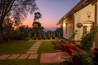 a garden of a house with a sunset in the background at Sliceinn Escapes Pushpanjali - Madikeri, Coorg in Madikeri