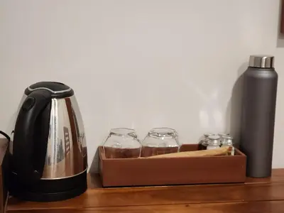 a black tea kettle and glasses on a wooden table at Mana Gramam Resort Mudumalai- Only For Indians,NRI in Mudumalai National Park