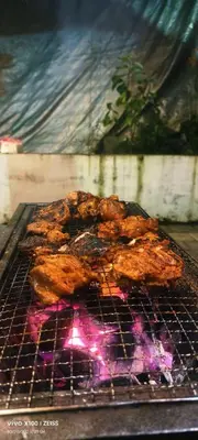 two pieces of meat cooking on a grill at The Bulbul Nest Homestay in Gūdalūr