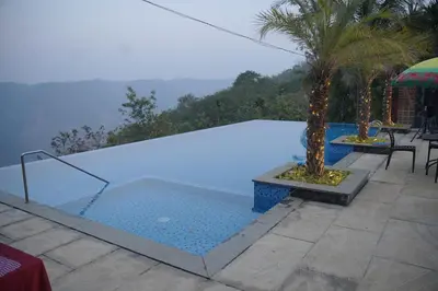 a swimming pool with a palm tree in the middle at Silver Oak Resort Wayanad in Chithragiri