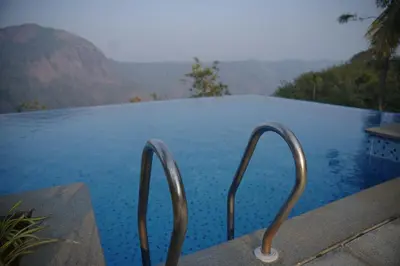 a swimming pool with a view of the water at Silver Oak Resort Wayanad in Chithragiri