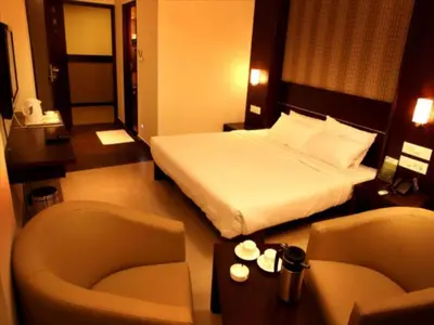 a hotel room with a bed and a chair at Sunflower Hotel in Mysore
