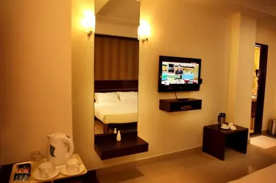 a room with a bedroom with a bed and a mirror at Sunflower Hotel in Mysore
