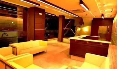 a living room with white furniture and a kitchen at Sunflower Hotel in Mysore