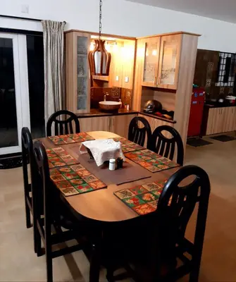 a dining room table with chairs and a kitchen at Greendale in Kotagiri