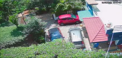 a red car parked in the driveway of a house at The Bulbul Nest Homestay in Gūdalūr