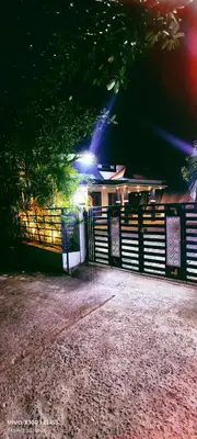 a house with a fence and lights on it at The Bulbul Nest Homestay in Gūdalūr