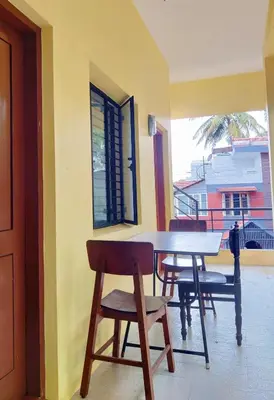 a table and chairs in a room with a window at Manasthala- Srinivas House Room1 in Mysore
