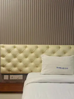 a bed with a tufted headboard in a room at Barkah inn in Kannur