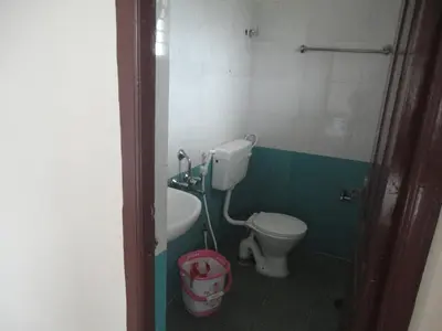 a bathroom with a toilet and a bucket in it at Sanvika Hotels & Service Apartments in Coimbatore