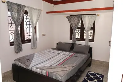 a bed in a bedroom with two windows at Lands End in Madikeri