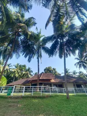 a house with palm trees in front of it at Bharathapuzha resort in Kārakkād