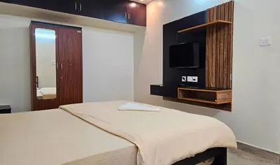 a bedroom with a bed and a flat screen tv at Mookambika Serviced Apartment in Coimbatore
