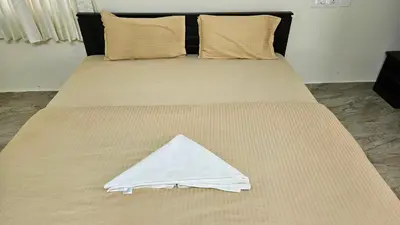 a bed with a white sheet on top of it at Mookambika Serviced Apartment in Coimbatore