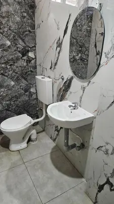 a bathroom with a toilet and a sink and a mirror at Mookambika Serviced Apartment in Coimbatore