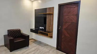 a room with a chair and a television and a door at Mookambika Serviced Apartment in Coimbatore