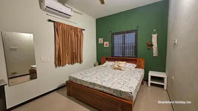 a bedroom with a bed and a green wall at SHI's Shenba 3BHk Villa Near Ganga Hospital Coimbatore in Coimbatore
