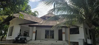 a house with a palm tree in front of it at Bharathapuzha villa in Kārakkād