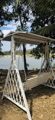 a swing on the beach with a tree and water at Bharathapuzha villa in Kārakkād