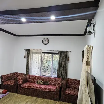 a living room with a couch and a clock on the wall at Mysticgreens Home Stay in Piriyāpatna