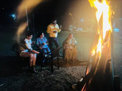 a group of people sitting around a fire at Mysticgreens Home Stay in Piriyāpatna