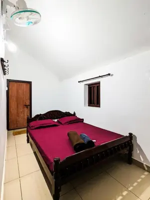 a bedroom with a large bed with red sheets at Wintervilla Cottages in Meppādi