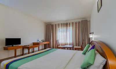 a hotel room with a bed and a desk at Treebo Sadhoo Heritage in Kannur