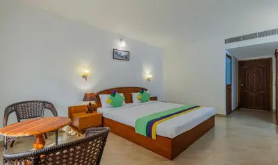 a bedroom with a bed and a table and chairs at Treebo Sadhoo Heritage in Kannur
