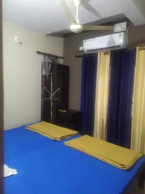 a bedroom with two beds with blue sheets and curtains at Mayoorvihar home stay Sulthaan Bathery Wayanad Kerala in Sultan Bathery