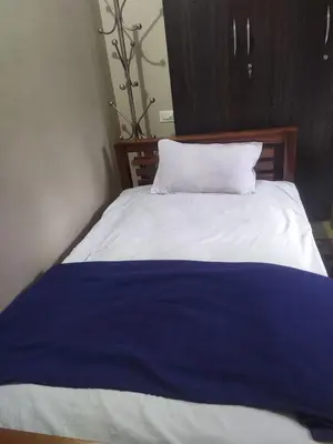a bed with a blue and white blanket on it at Mayoorvihar home stay Sulthaan Bathery Wayanad Kerala in Sultan Bathery