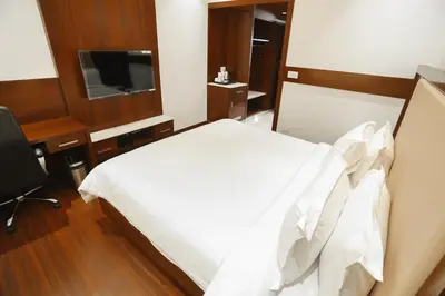 a bedroom with a bed and a desk and a television at Hotel Lakshmi Towers in Kāngayam