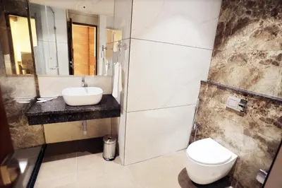 a bathroom with a sink and a toilet and a mirror at Hotel Lakshmi Towers in Kāngayam