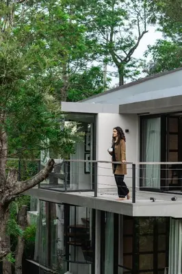 a woman standing on a balcony talking on a cell phone at LohonoStays Amani Villa 11A in Coonoor