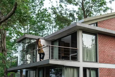 a woman standing on the balcony of a house at LohonoStays Amani Villa 11A in Coonoor