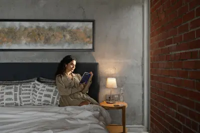 a woman sitting on a bed reading a book at LohonoStays Amani Villa 12A in Coonoor