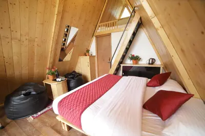 a bedroom with a bed in a room with wooden walls at Eagle Woods Kookal in Kūkkāl