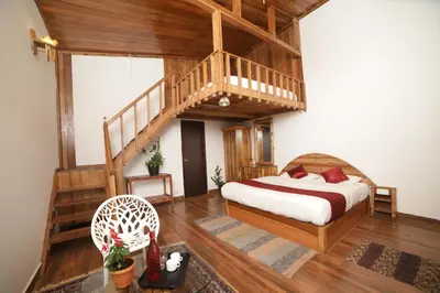 a bedroom with a bed and a wooden staircase at Eagle Woods Kookal in Kūkkāl