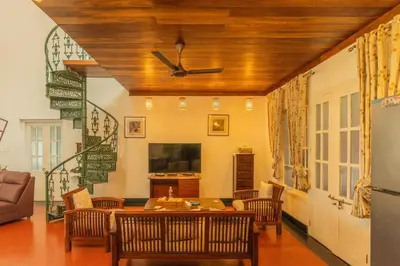 a living room with a table and a ceiling fan at Bougainville, Wayanad in Kalpetta