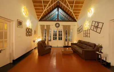 a living room with two couches and a clock on the wall at Bougainville, Wayanad in Kalpetta