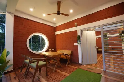 a patio with a table and chairs and a brick wall at Areca Valley Farmstay in Agali
