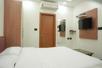 a bedroom with a white bed and a television at Theeram Residency in Iringal