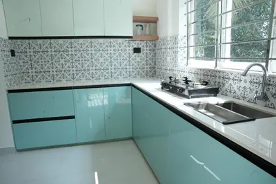 a kitchen with white cabinets and a sink at Theeram Residency in Iringal