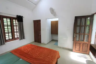 a room with a red blanket on the floor and a door at Wayanad One in Wayanad
