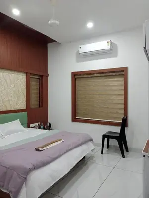 a bedroom with a bed and a window and a chair at Izzath in Kottakkal