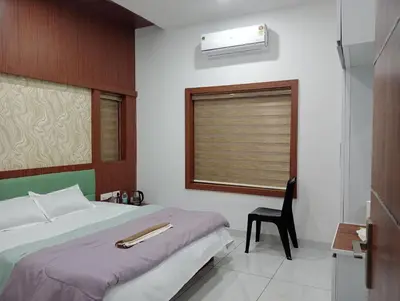 a bedroom with a bed and a chair and a window at Izzath in Kottakkal