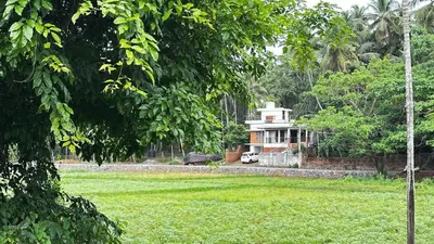 a house in the middle of a green field at Izzath in Kottakkal