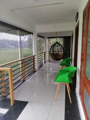 a balcony with green chairs and a swing at Izzath in Kottakkal