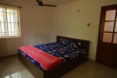 a bedroom with a bed with a blue comforter at Coimbatore's Chettinad Courtyard By Shivalaya Stays in Alāndurai